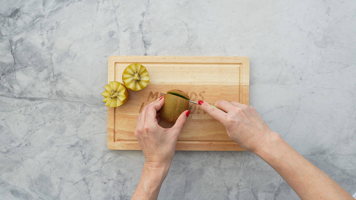 The end of the kiwi fruit being removed with a small sharp knife.