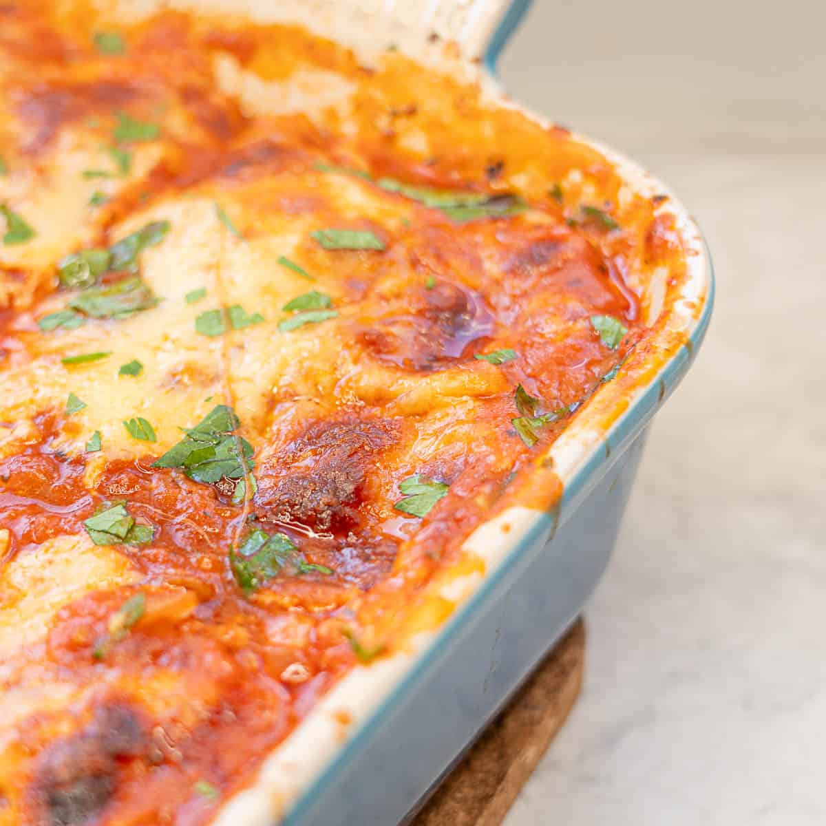 Corner of lazy lazing in baking dish showing melted cheese on top.