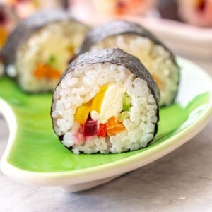 Piece of Rainbow Sushi on a plate showing ingredients inside.