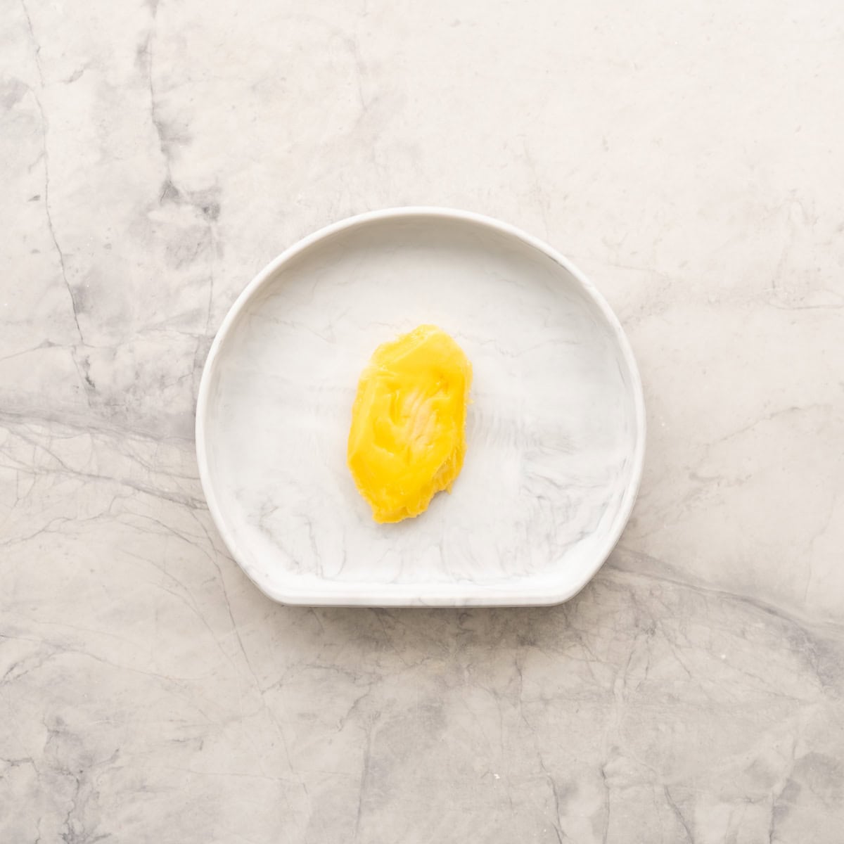 Mango pip with mango pulp around it sitting on baby silicone plate on benchtop.