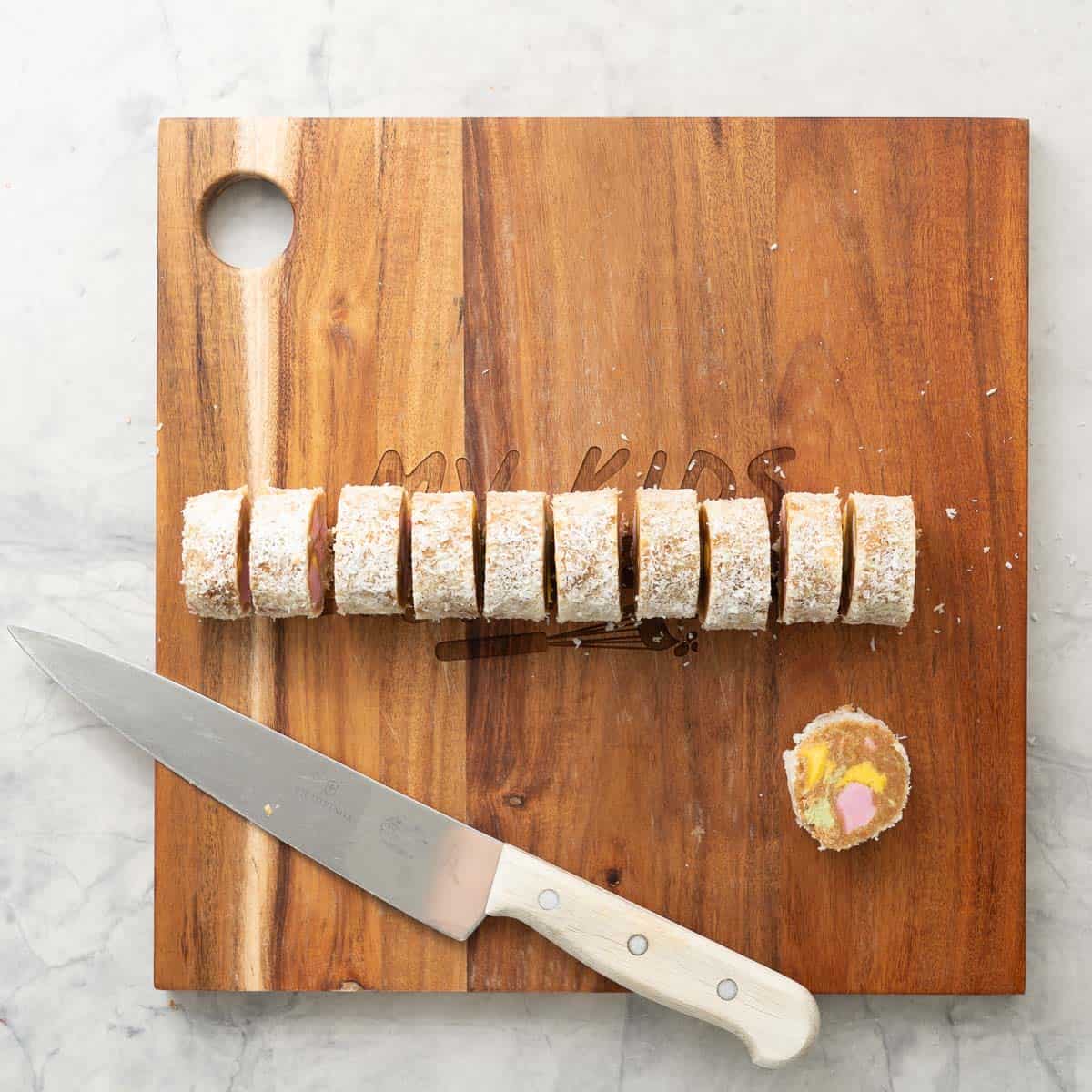 Wooden chopping board with lolly cake sliced into small circles.