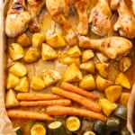Roasted chicken glazed in honey soy sauce roasted zucchini, carrots and potatoes on a baking tray.