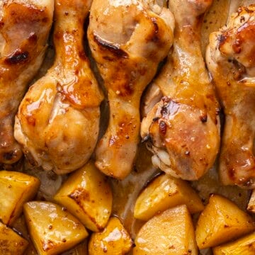 Roasted chicken and potatoes glazed in honey soy sauce on a baking tray.