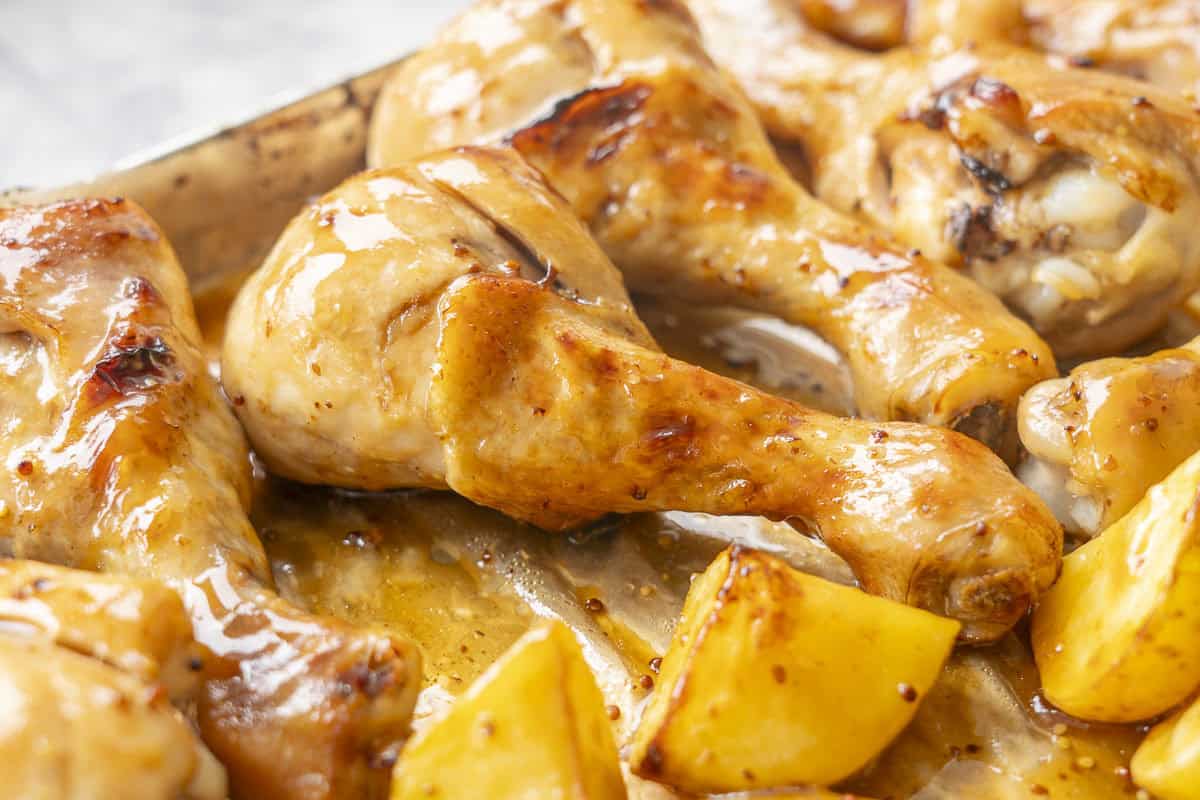 Roasted chicken glazed in honey soy sauce on a baking tray.