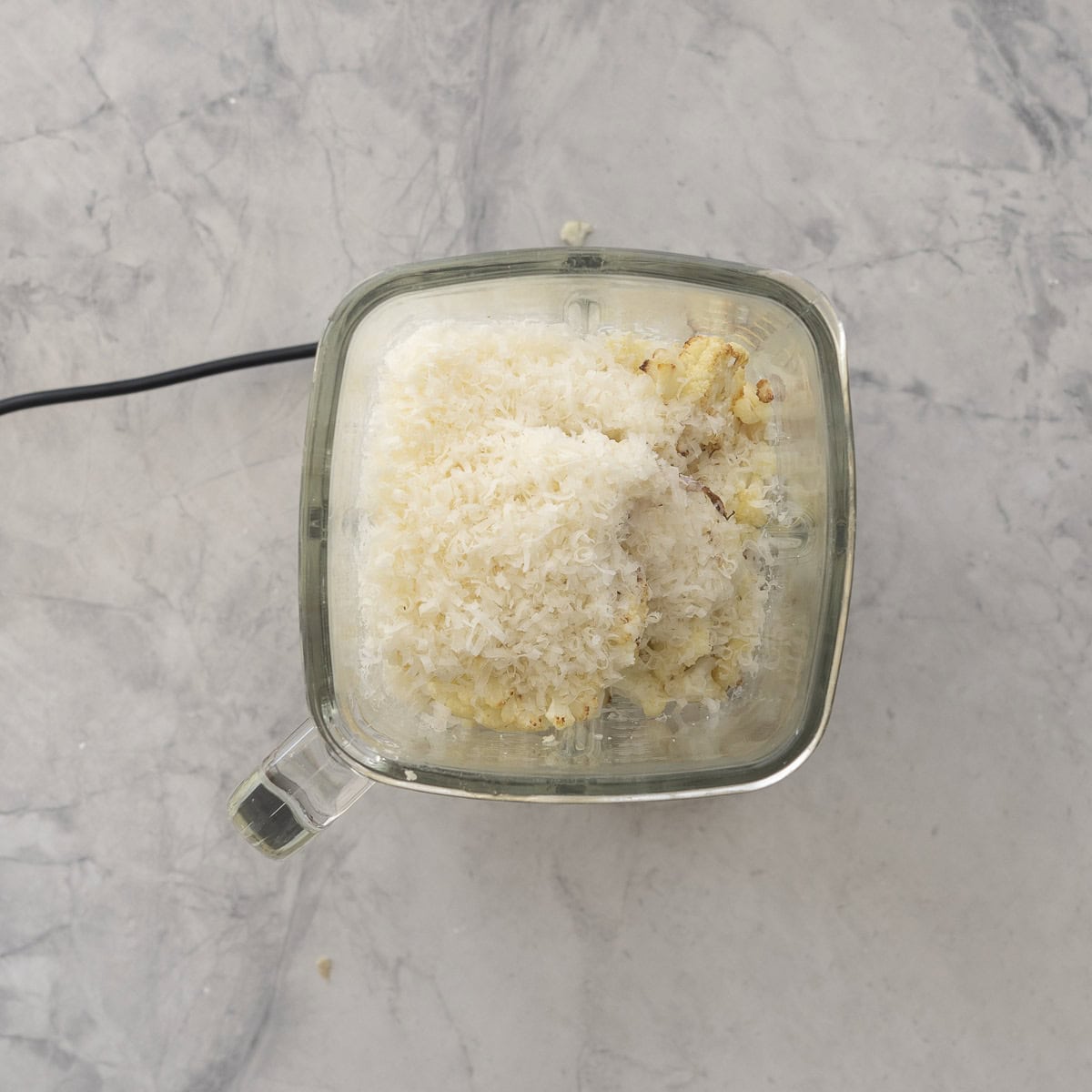 Roasted Garlic, parmesan cheese and milk in a food processor on benchtop.