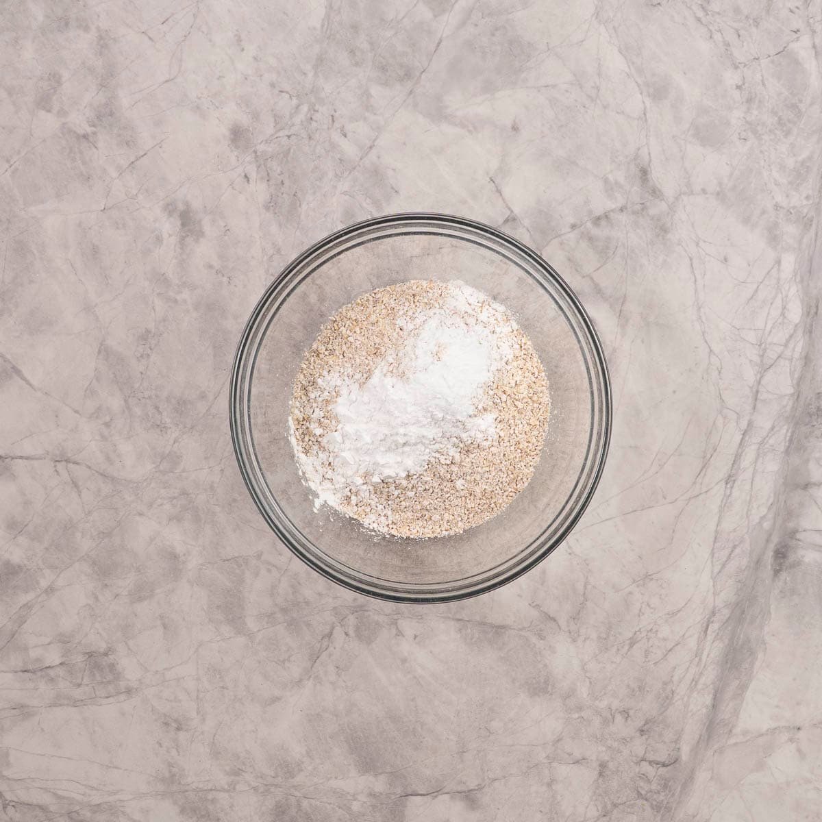 Dry ingredients for baby rusks in a large glass bowl on benchtop.