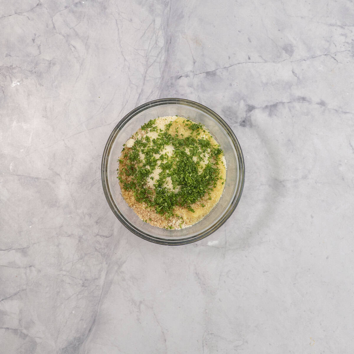 Ingredients for chicken parmesan in a glass bowl on benchtop.