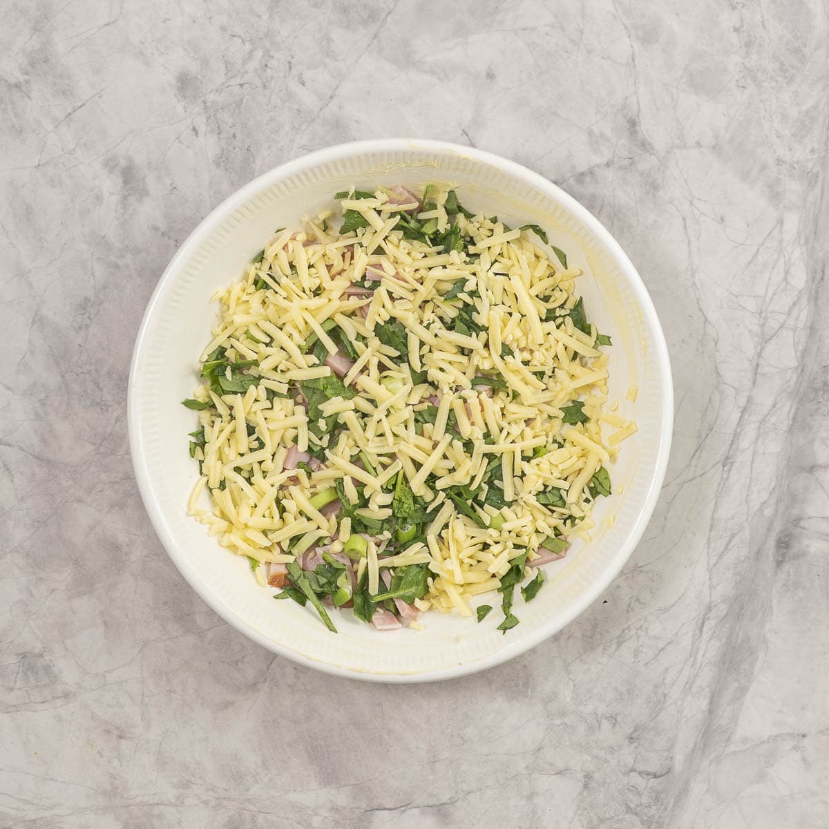 Cheese, ham, green onion and spinach on base of baking dish.
