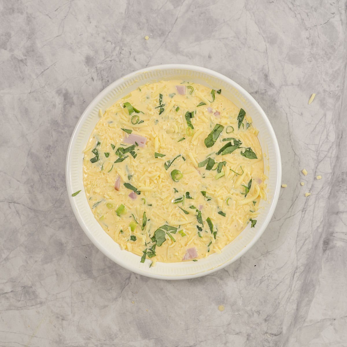 All ingredients for crustless quiche inside baking dish on benchtop.