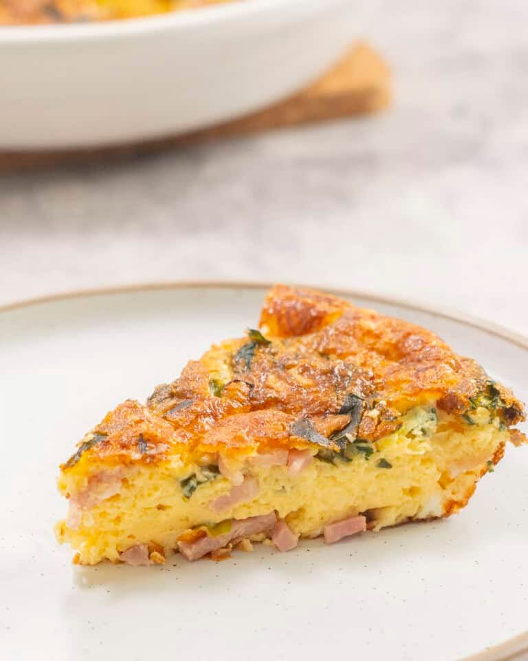 Slice of quiche on dinner plate.