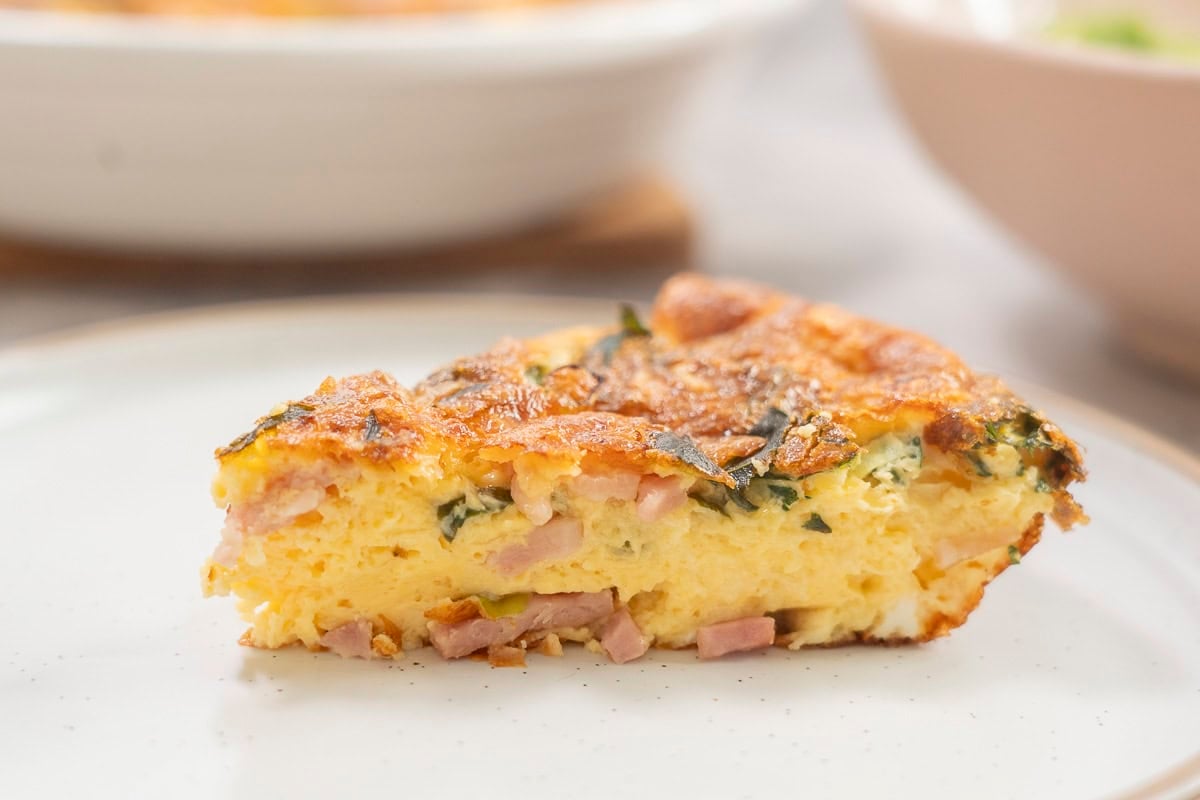 Slice of quiche on dinner plate.