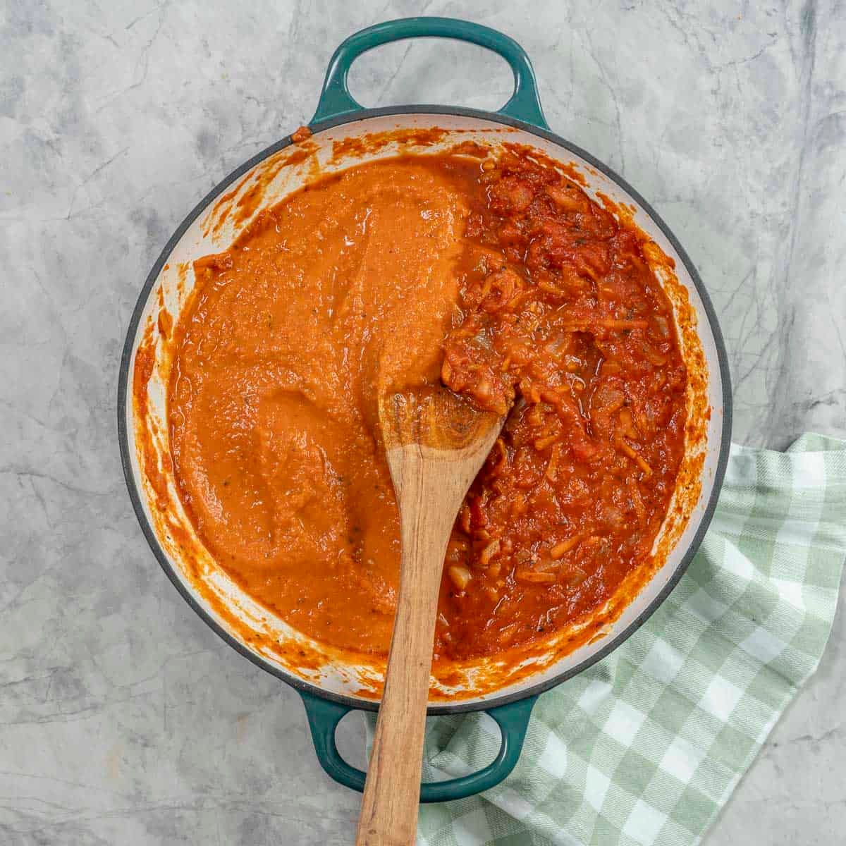 A pan of marinara sauce, half blended smooth, half chunky.