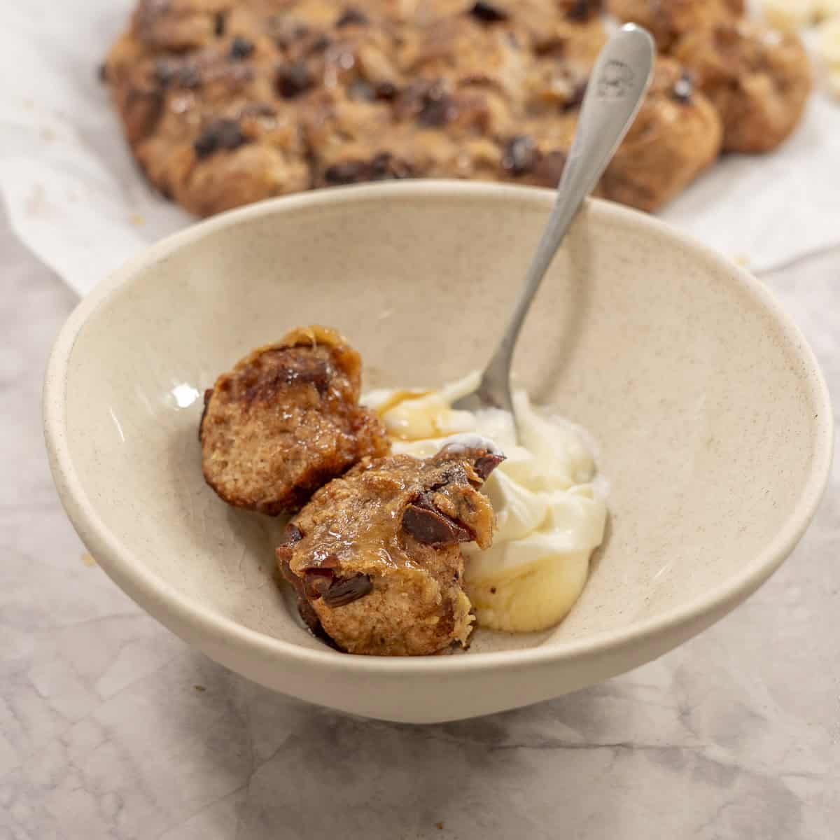 Desert bowl with monkey bread, yogurt and spoon inside.
