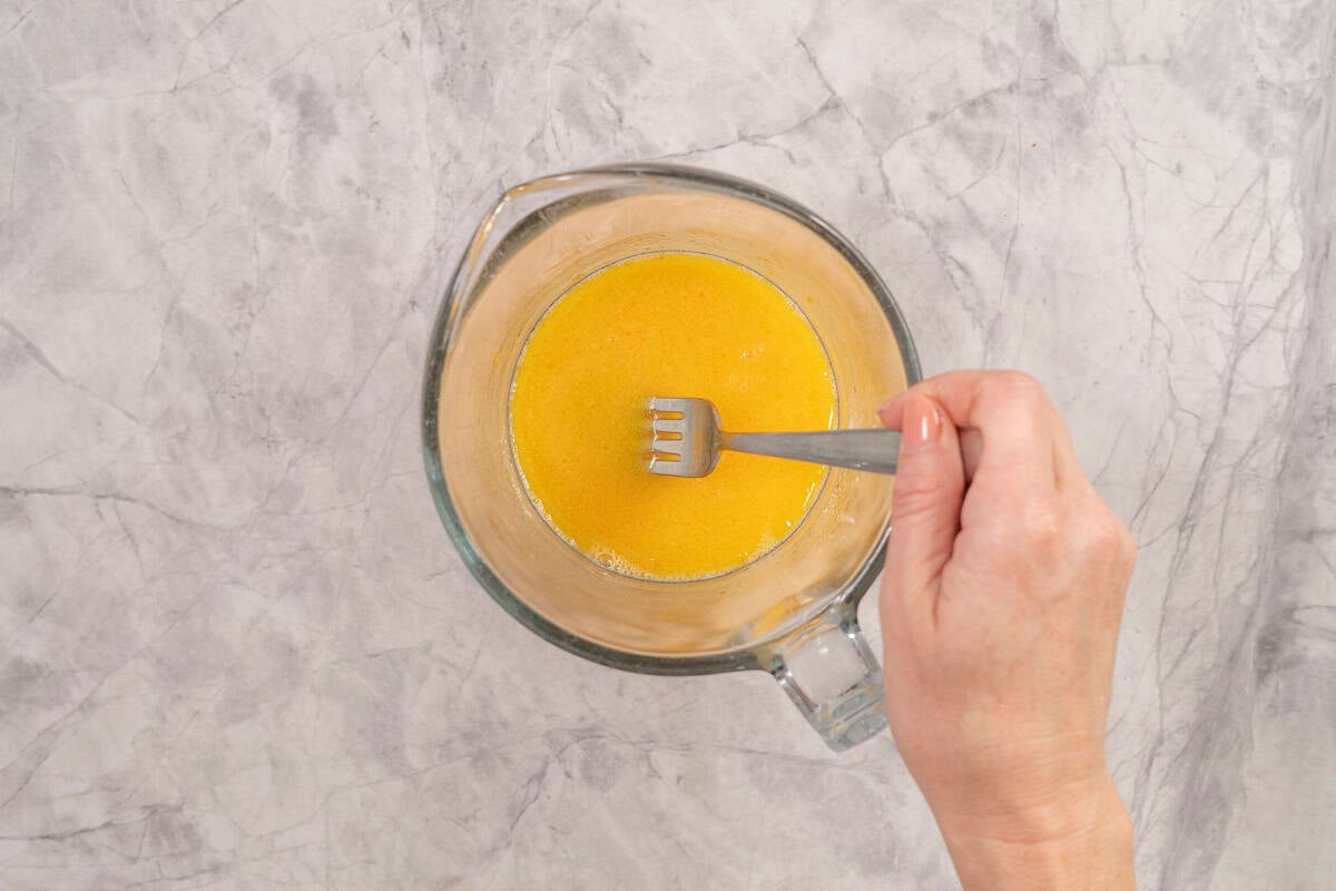 Hand holding a fork stirring wet ingredients together.