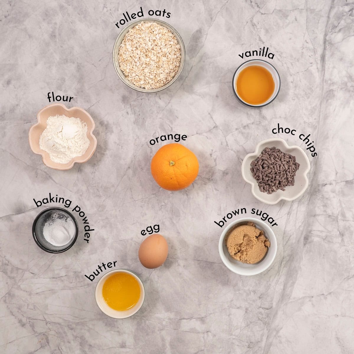 Ingredients for orange oatmeal cookies on benchtop with text overlay.