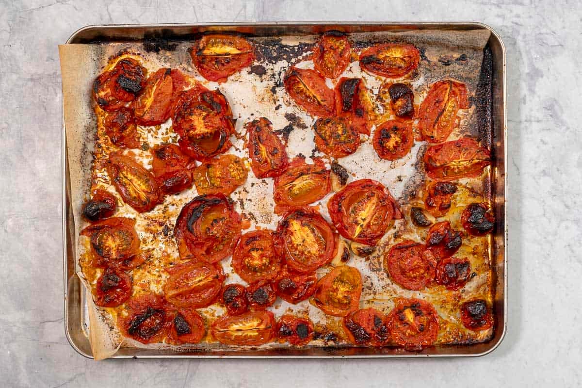 Chopped tomatoes roasted on lined baking tray.