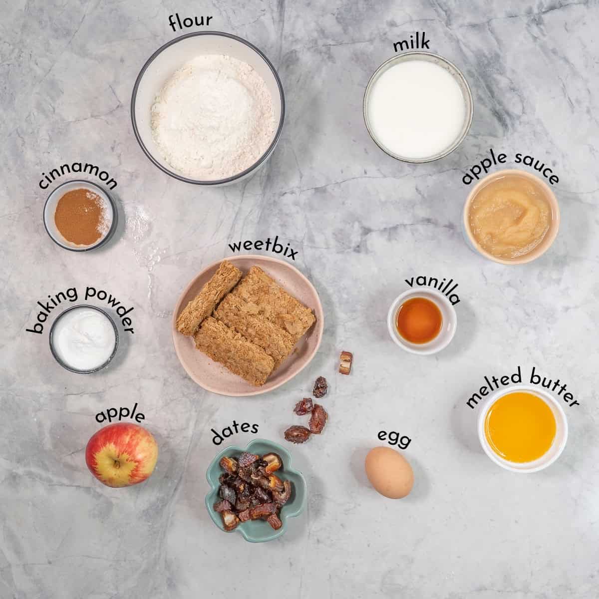 Ingredients for weetbix muffins on benchtop with text overlay.