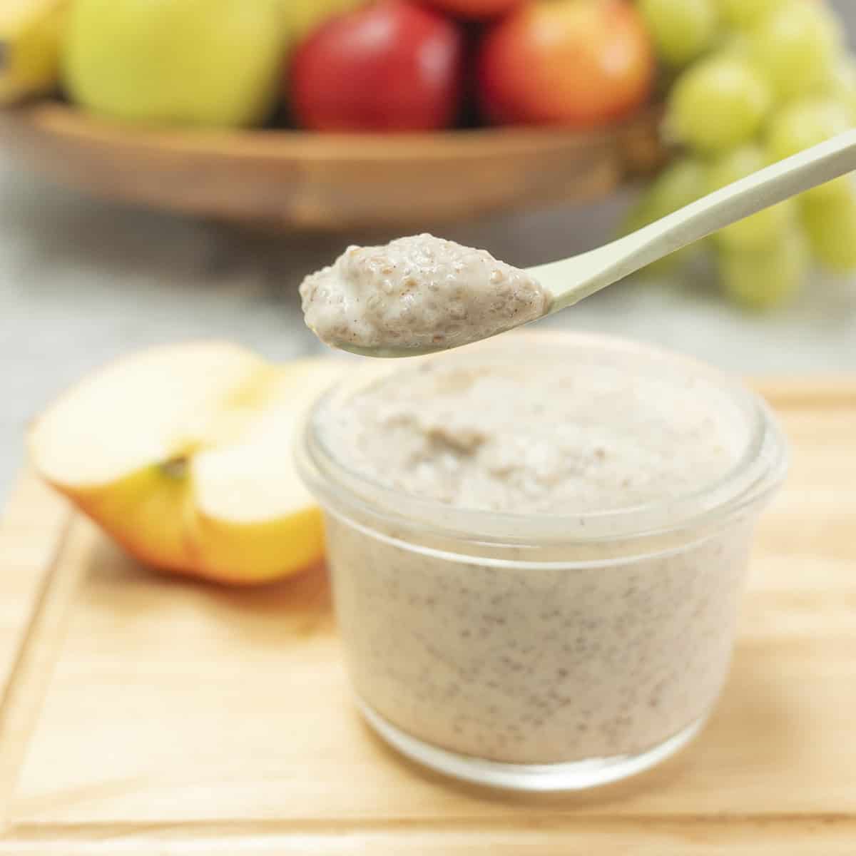 Chia seed pudding in a small glass container being scooped out with a green bamboo spoon.