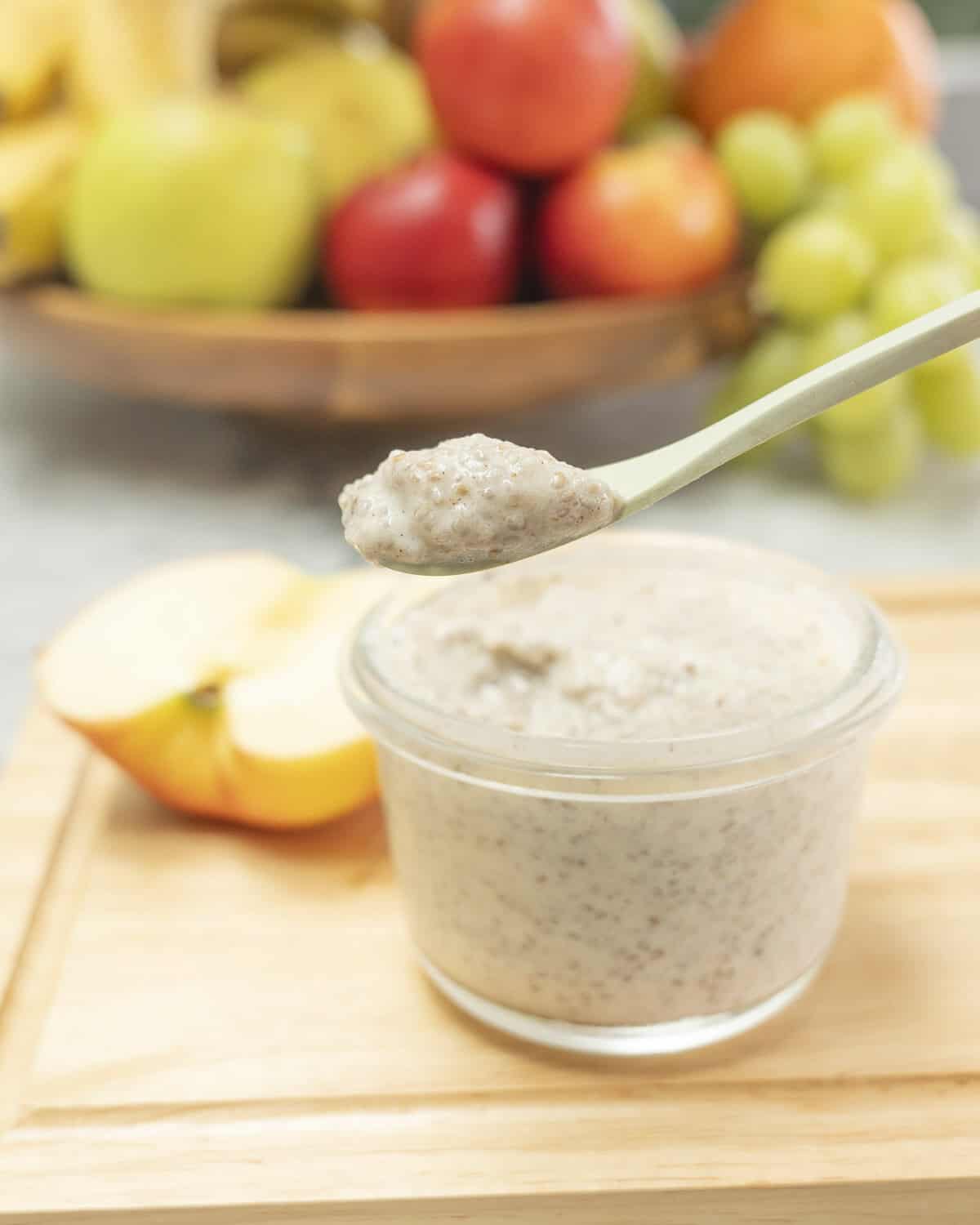 Chia seed pudding in a small glass container being scooped out with a green bamboo spoon.