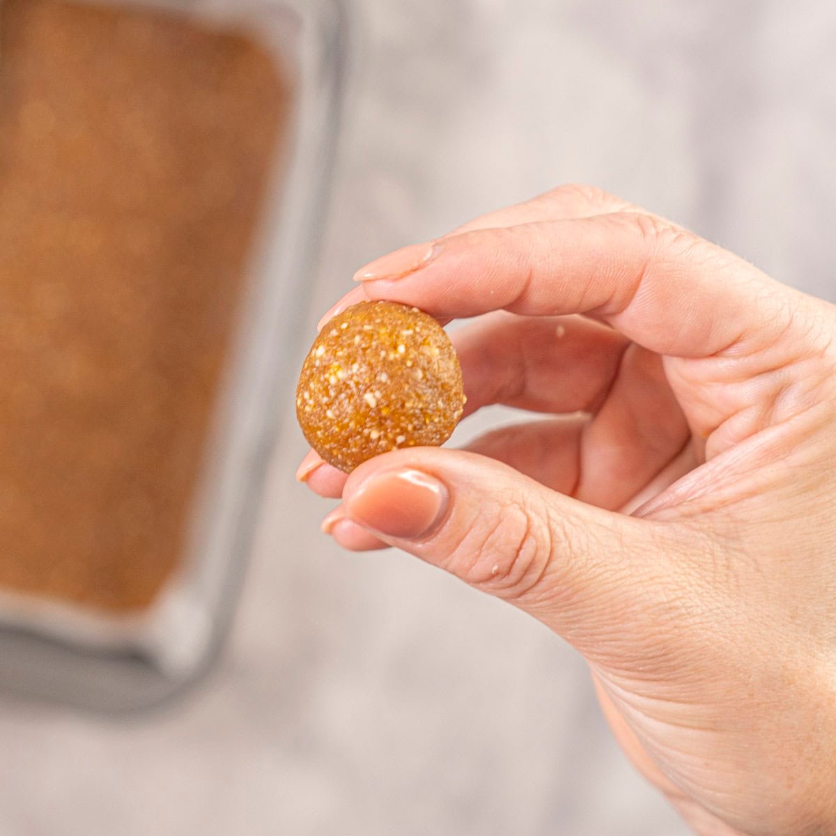 Womans hand holding a small apricot ball.