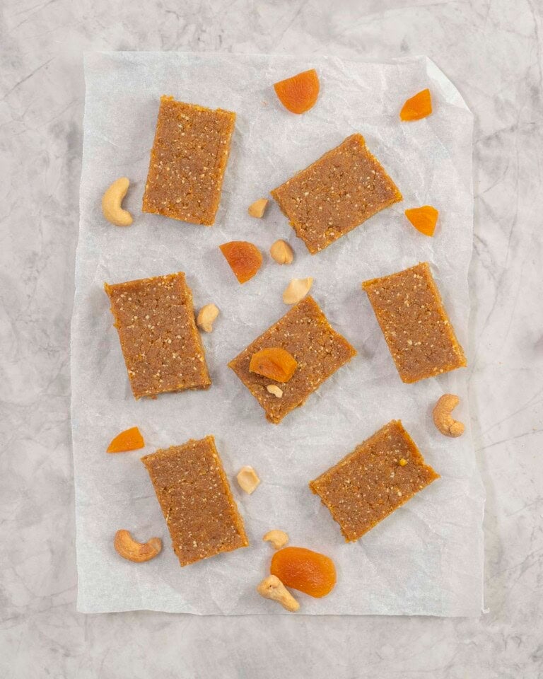 Apricot bars on baking paper with sprinkled cashews and sliced dried apricots.