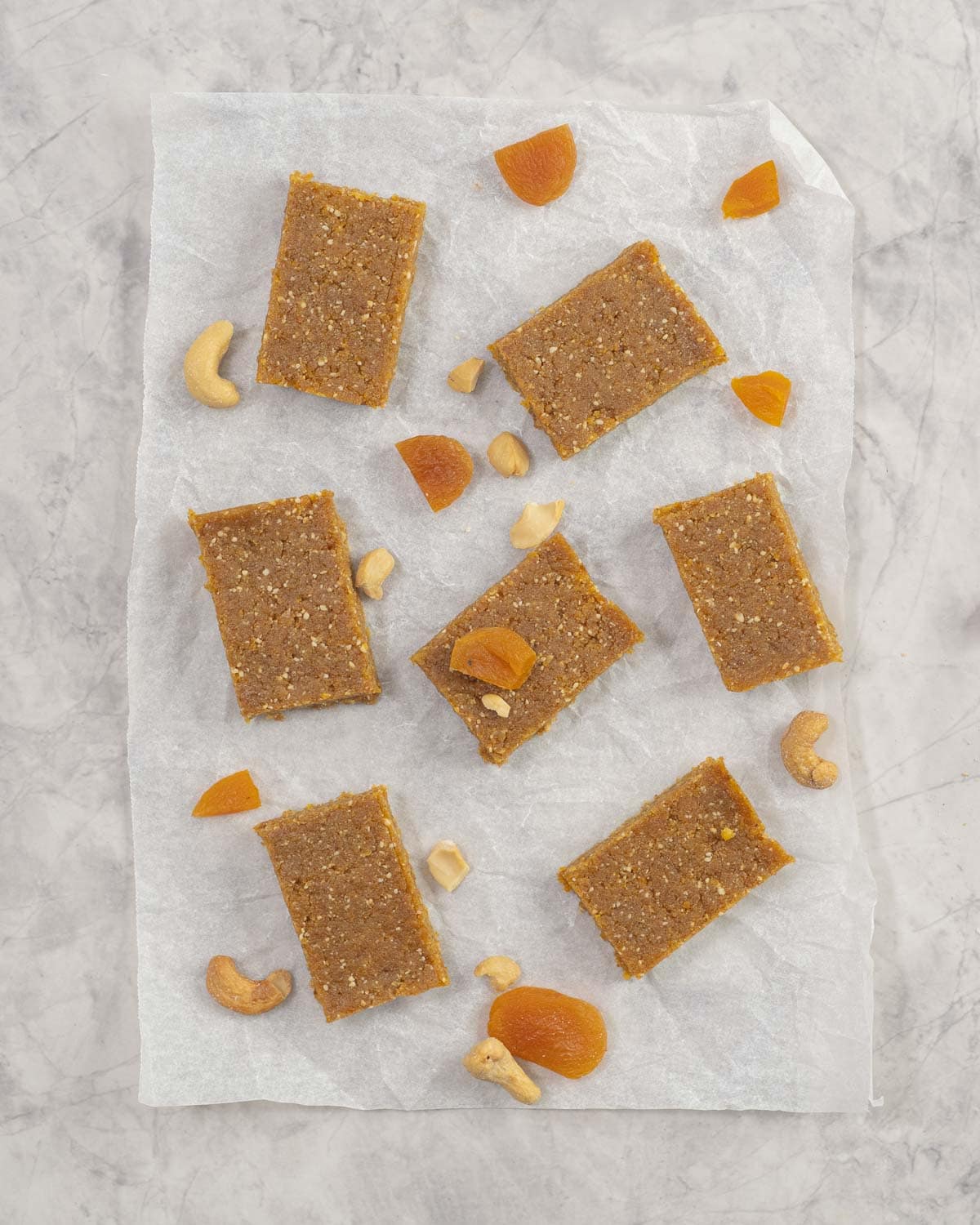 Apricot bars on baking paper with sprinkled cashews and sliced dried apricots.