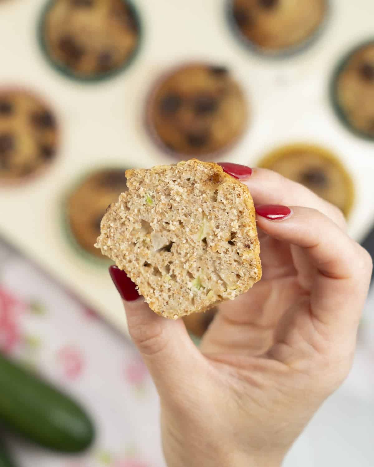 Hand holding a muffin cut in half showing the inside.