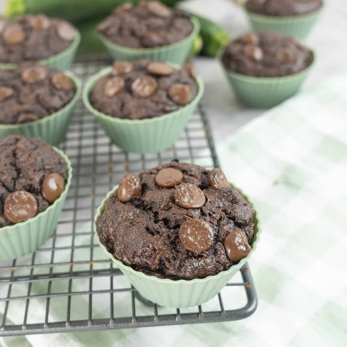 Chocolate chip muffins in green silicone cold on a cooling rack.