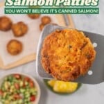 Metal spatula with salmon pattie held up, wooden chopping board with remainder of patties, bowl of fresh salad and corn below. Text overlay: The best salmon patties, you won't believe it's canned salmon!
