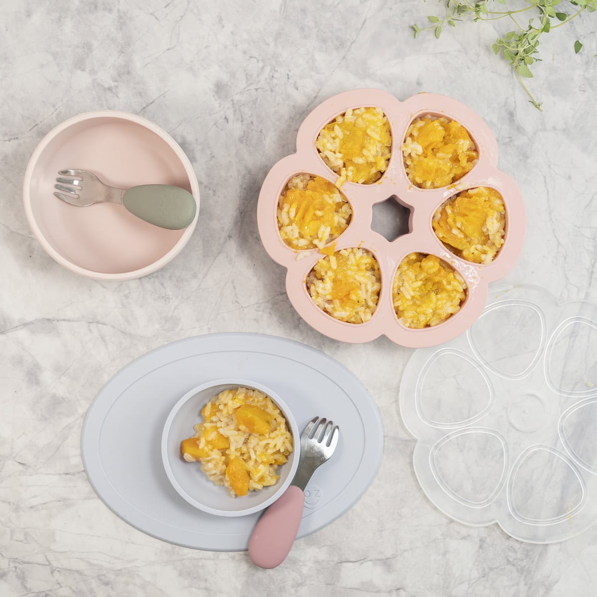 Pink circle freezer silicone mould with baked risotto inside, silicone baby bowls on benchtop.