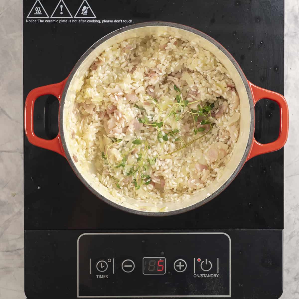 Ingredients for baked risotto in cast iron pan on stove top.