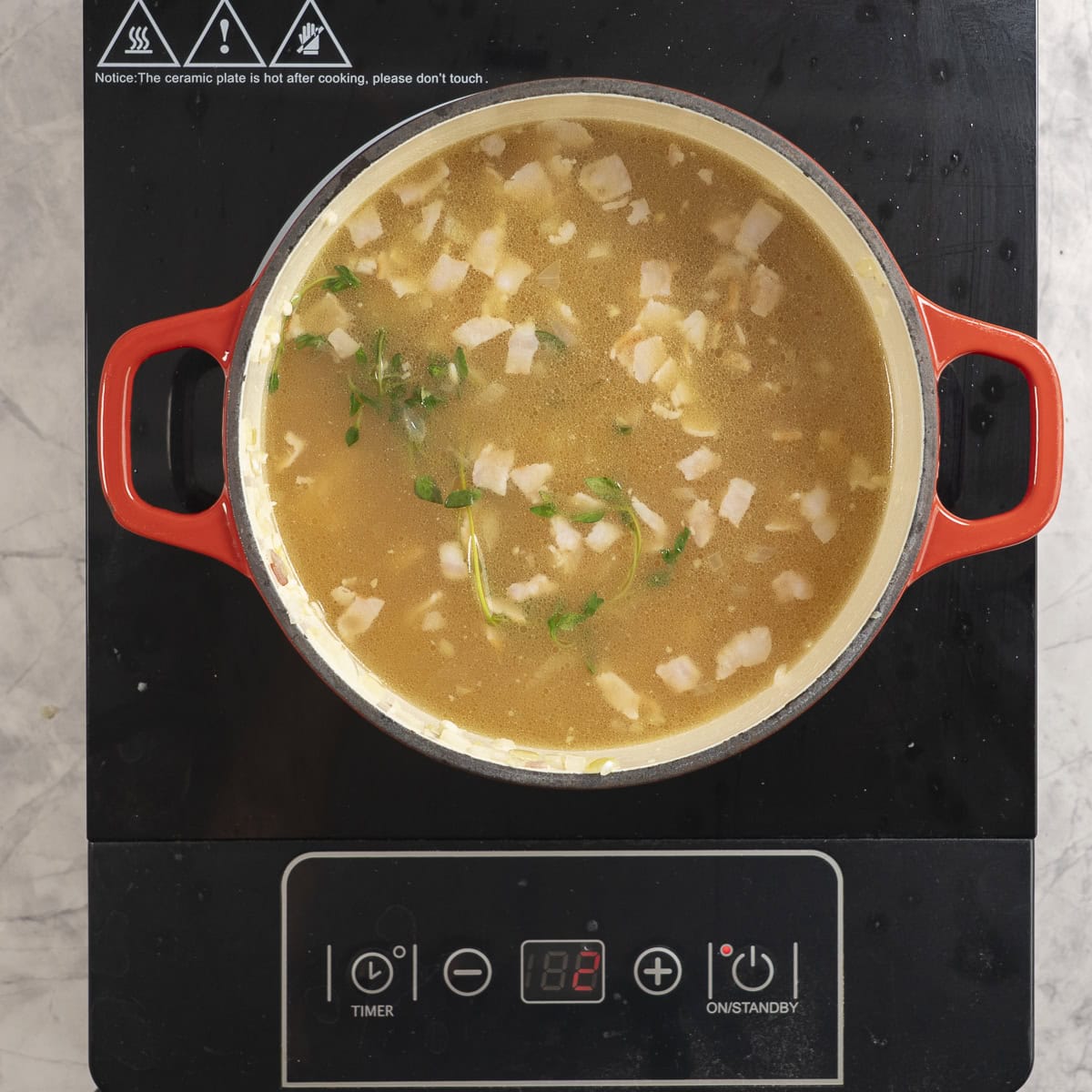 Broth added into ingredients in pan on stove top.