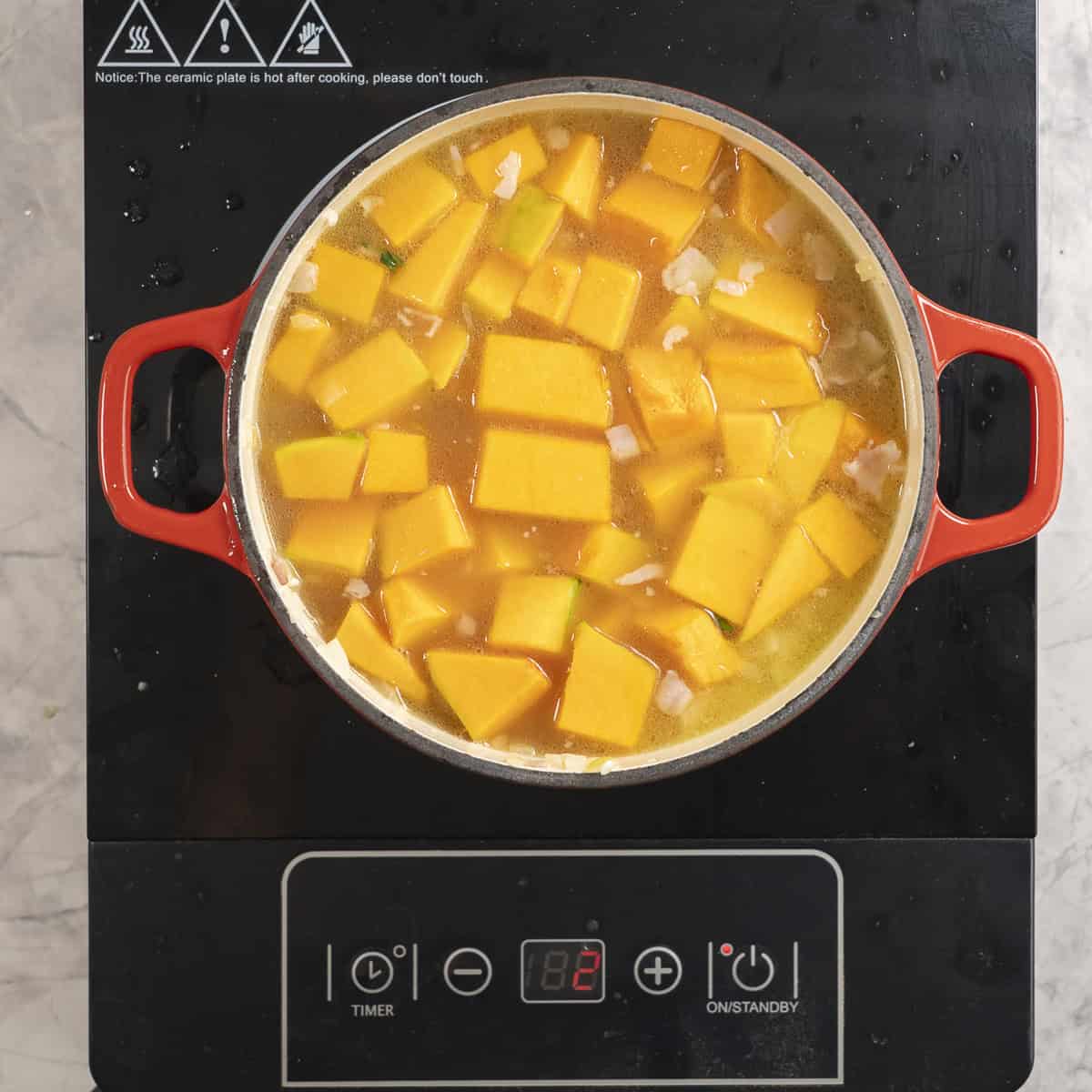 Chopped pumpkin added into stock on stove top.
