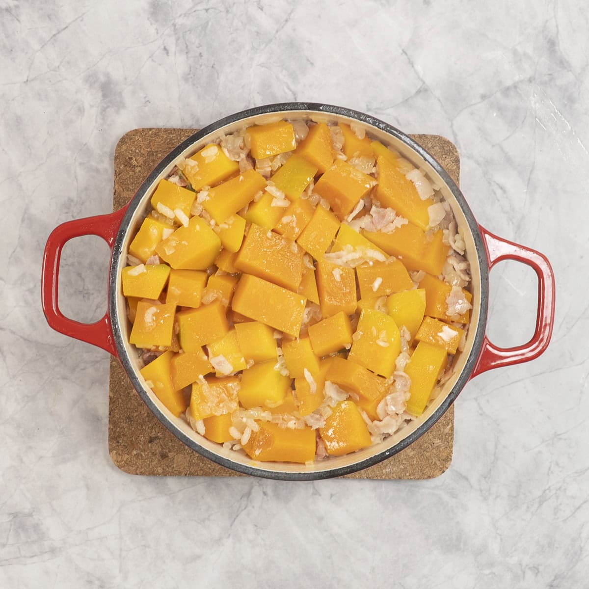 Pan on cork board on benchtop, cooked pumpkin and risotto inside.