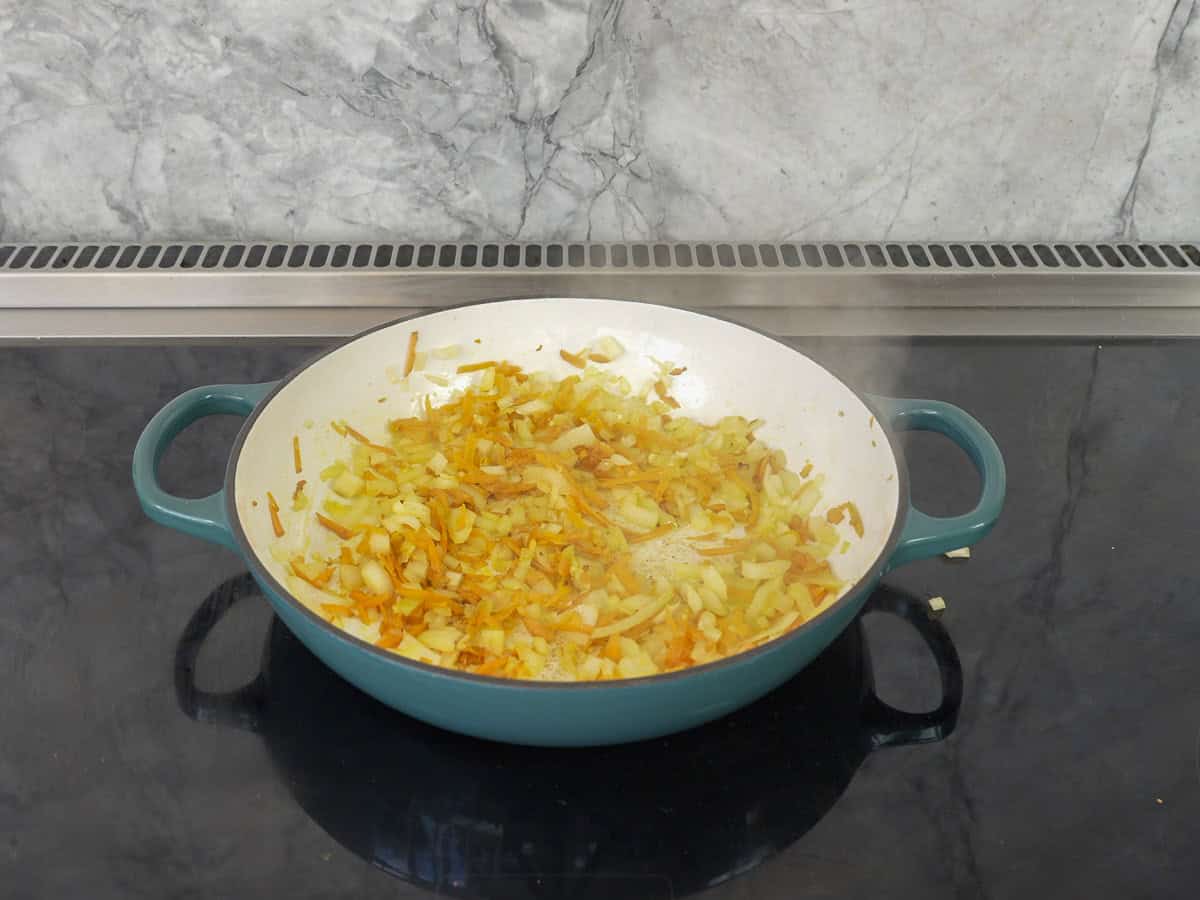 Onion and grated garlic cooking in a ceramic pan.