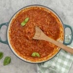 A pan of marinara sauce garnished with basil leaves.