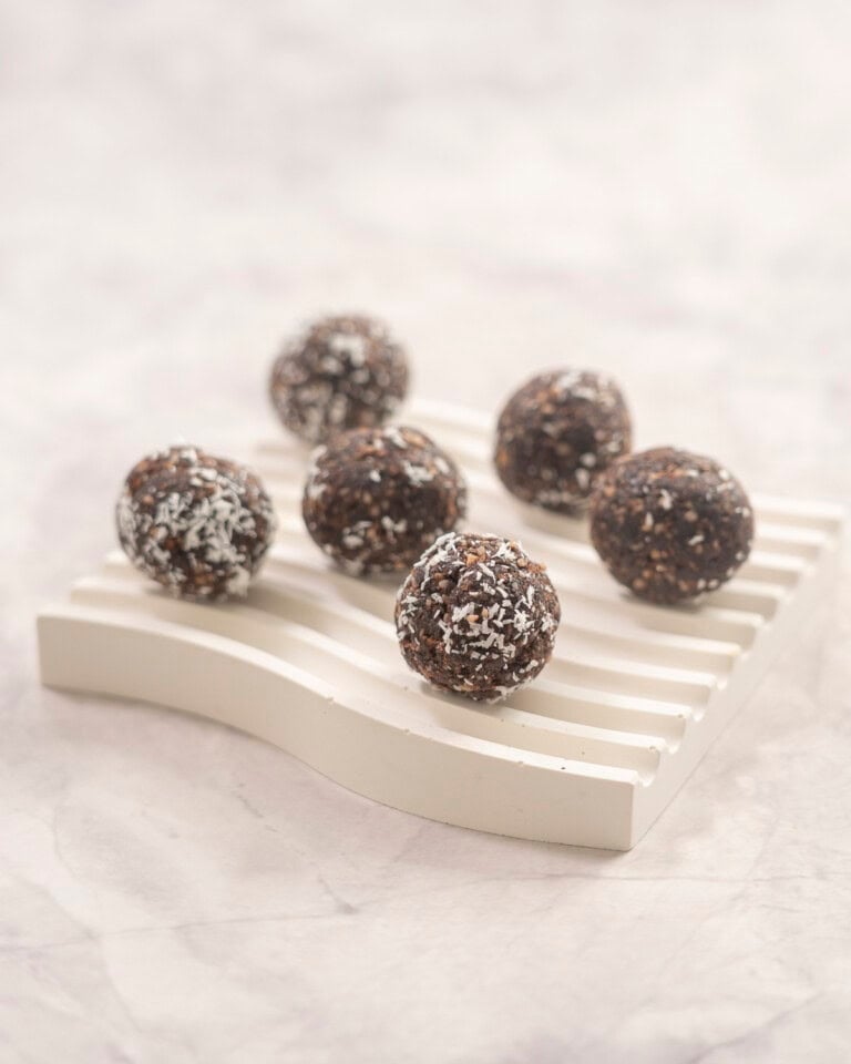 Six weetbix bliss balls on small ramekin on benchtop.