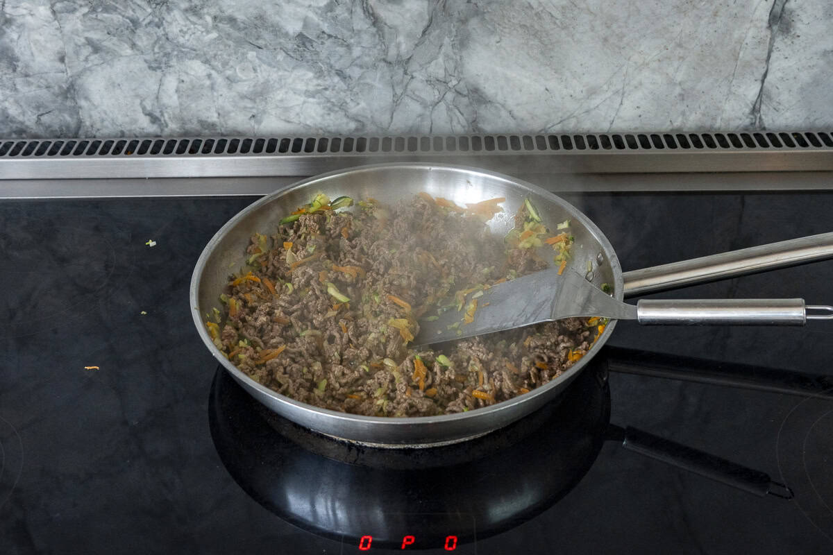 Browned mince with cooked grated vegetables in a stainless steel skillet.