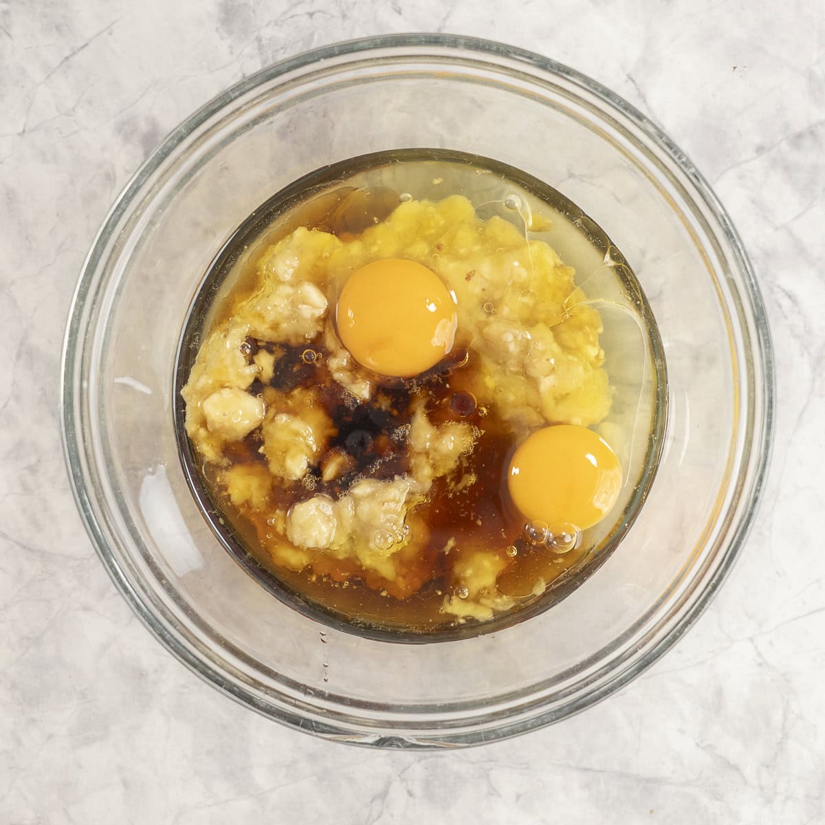 Wet ingredients in big glass bowl on bench top.