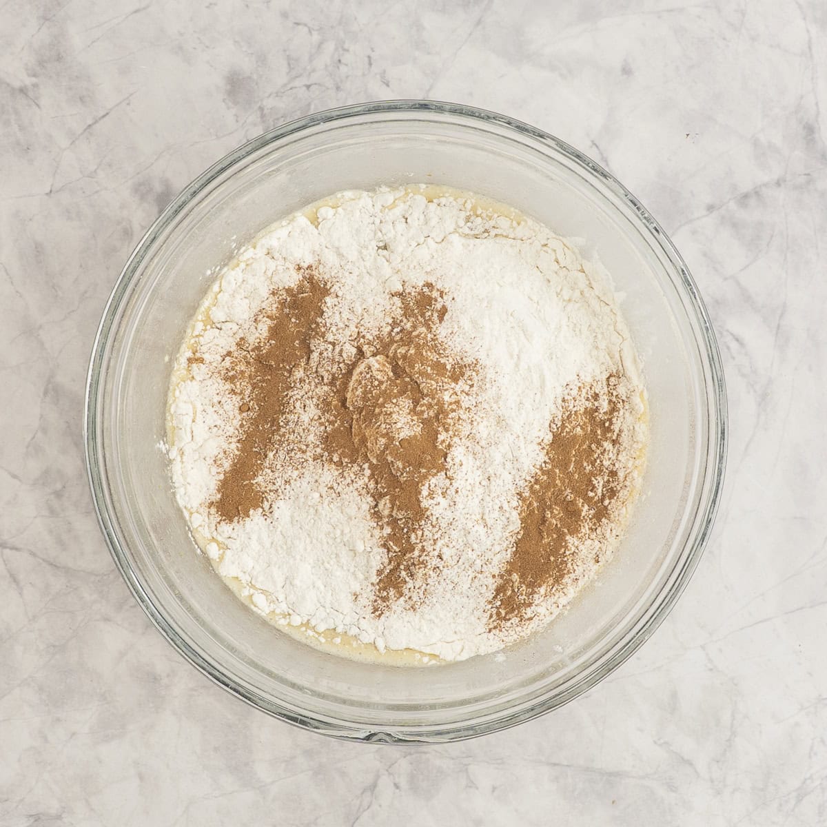 Dry ingredients added into bowl of wet ingredients in glass bowl.