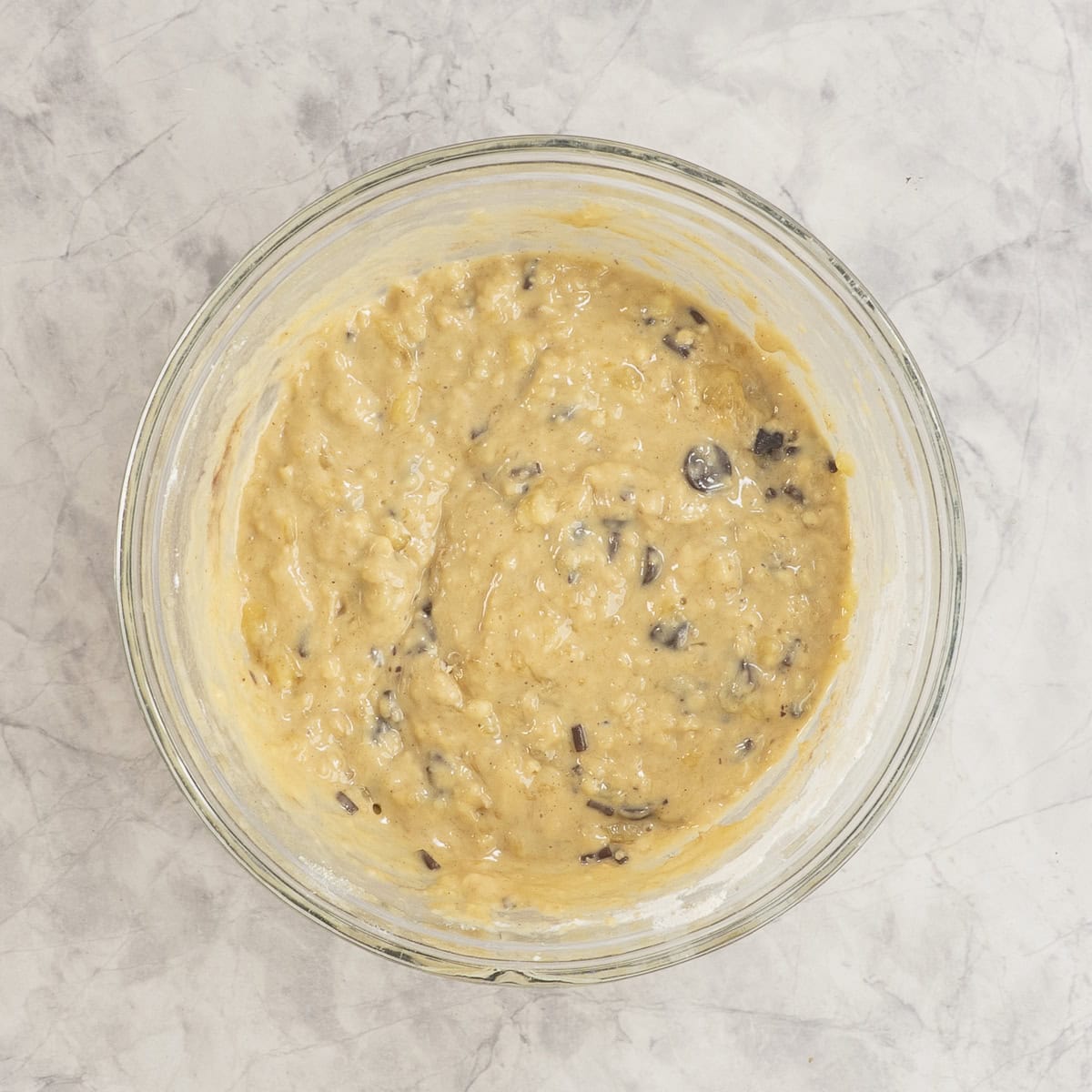 Muffin batter with chocolate chips mixed together in glass bowl.
