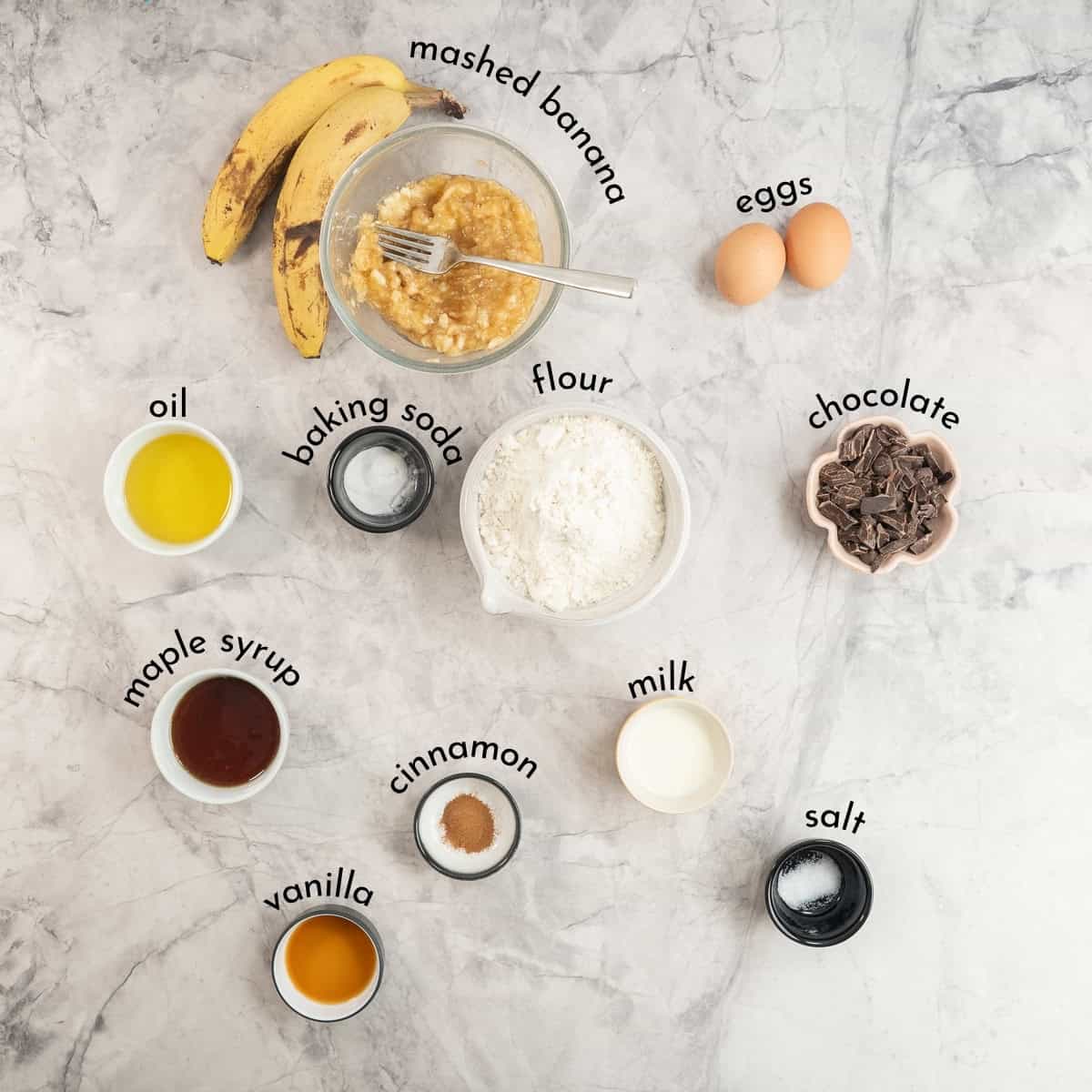 Ingredients for Banana chocolate chunk muffins on benchtop with text overlay.