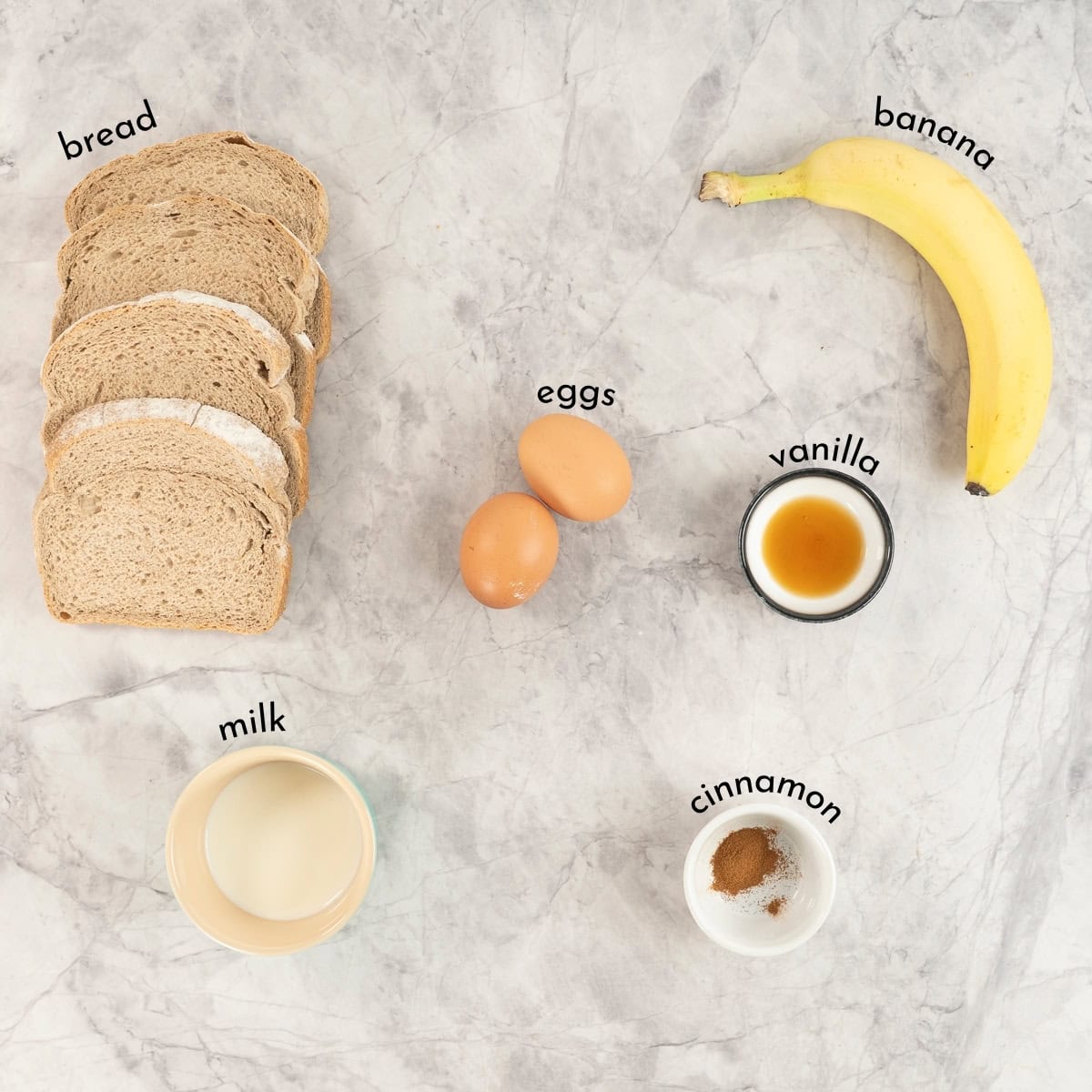 Slices of bread, eggs, milk, banana, vanilla and cinnamon on a bench to with text overlay.