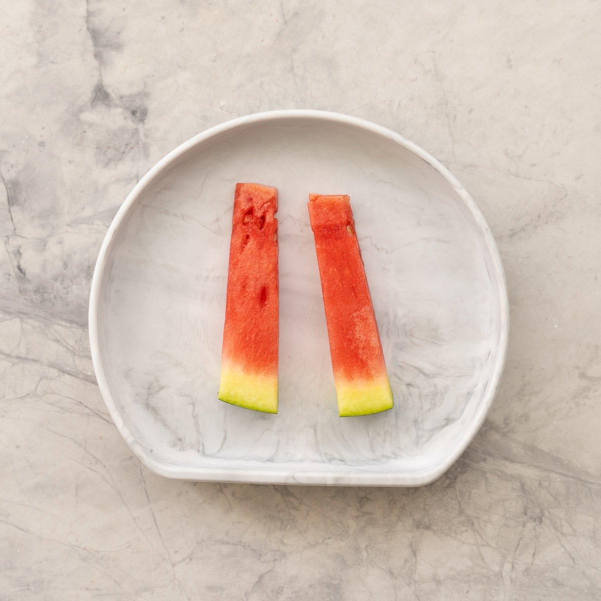 Two batons of watermelon on a baby plate.