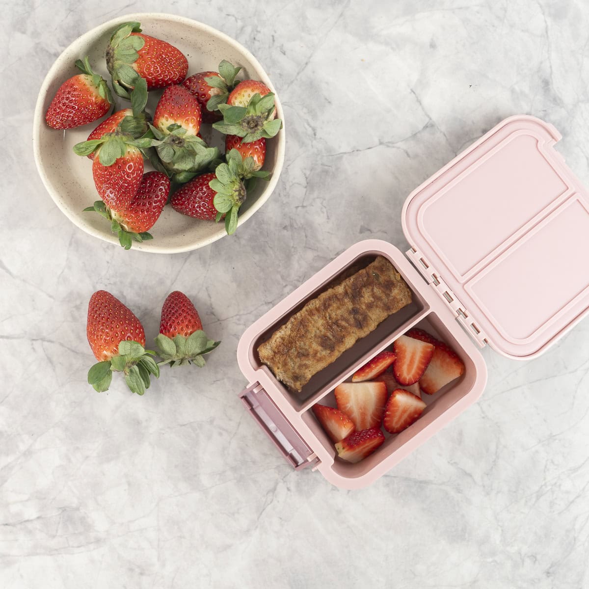 French toast and strawberries packed into a pink lunch box.
