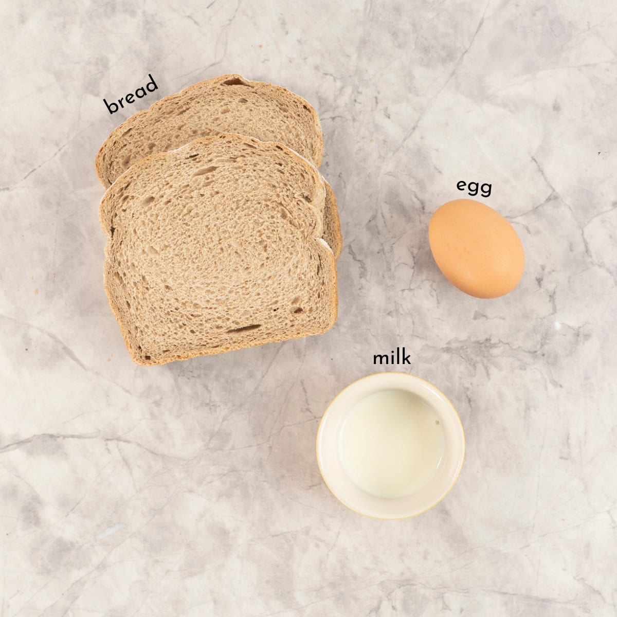 Ingredients for eggy bread on marble bench top with text overlay.