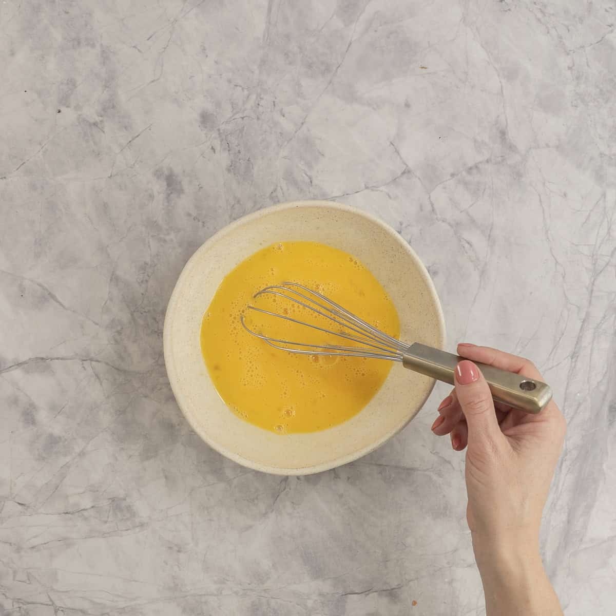 Eggs in a bowl being whisked together.