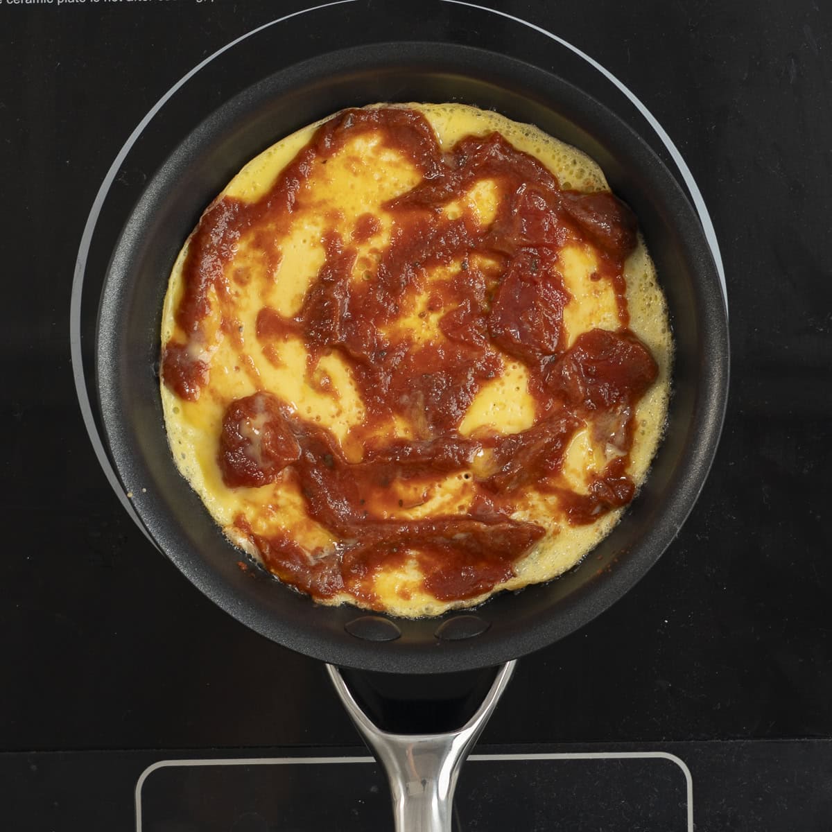 Tomato paste added ontop of cooked egg in skillet.