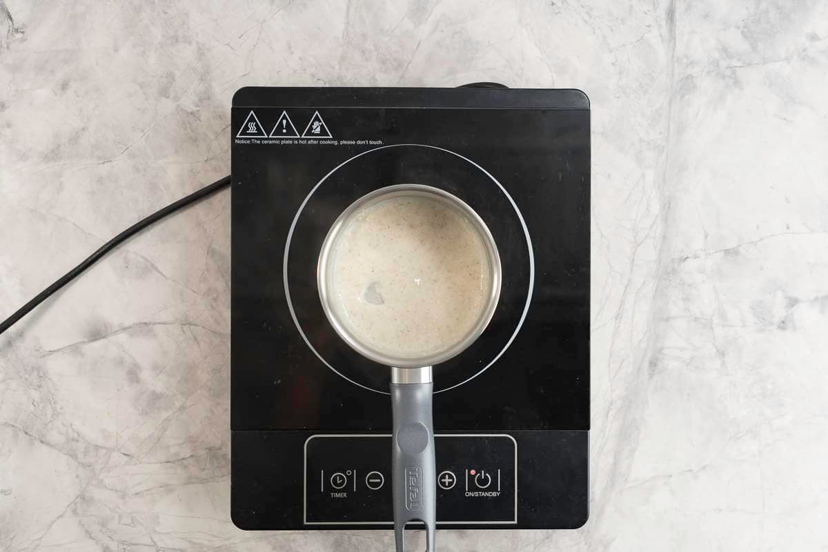 Small pot sitting on an electric stove top with creamy oats inside.