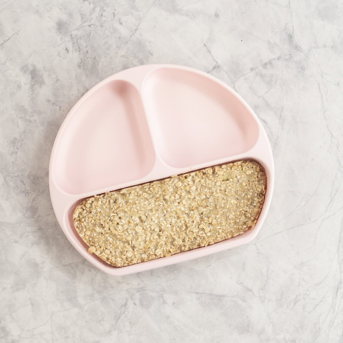 Cooked porridge in pink silicone toddler plate.